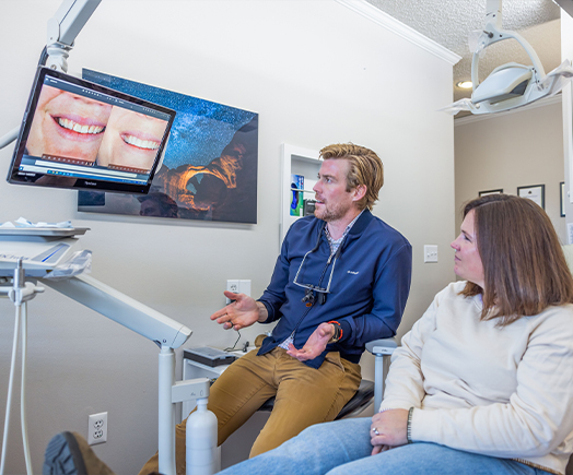 Man in dental chair shaking hands with dentist