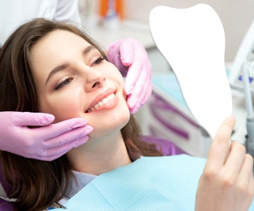 patient smiling while looking in dental mirror