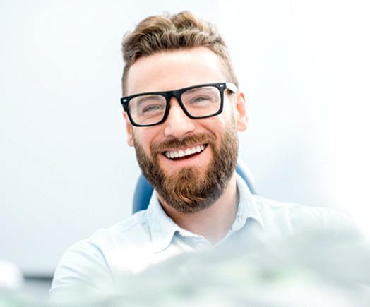 man smiling while sitting in dental chair