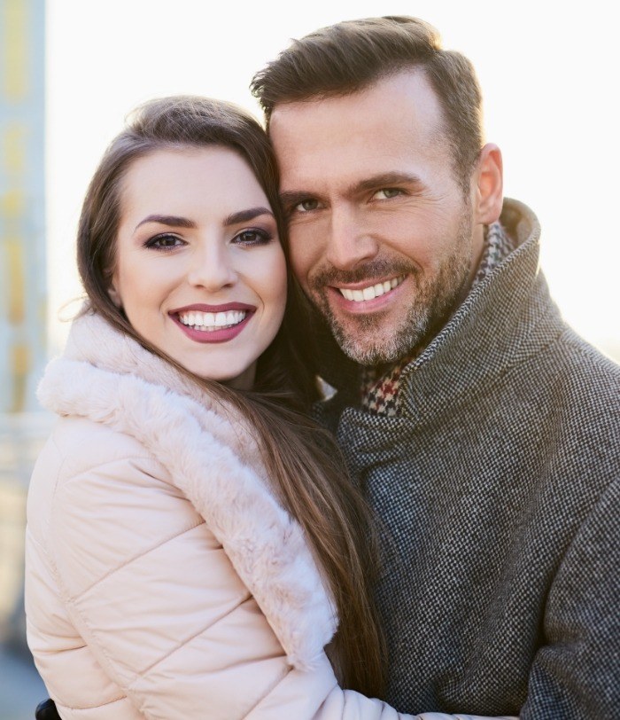 Man and woman in winter coats smiling after cosmetic dentistry in Centennial