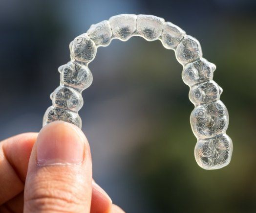 Hand holding an Invisalign clear aligner