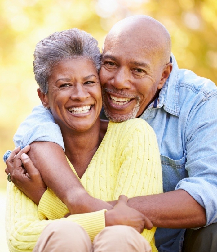 Senior man and woman hugging and smiling with dental implants in Centennial