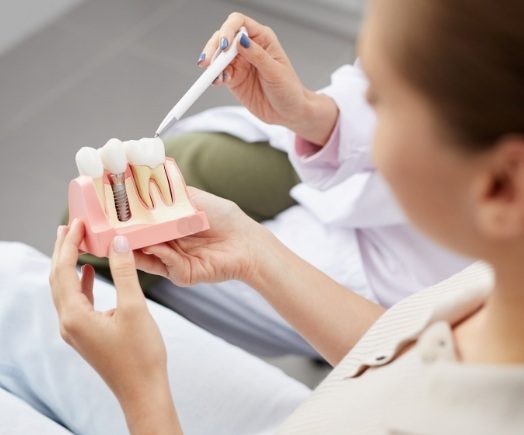 Dentist showing a patient a model of a dental implant