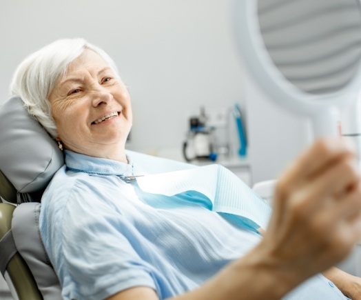 Senior dental patient admiring her smile in a mirror