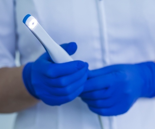 Two gloved hands holding an intraoral camera