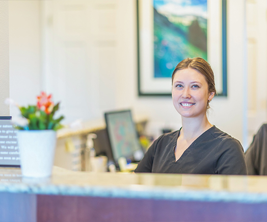 Mother and young daughter talking to dental team member at front desk