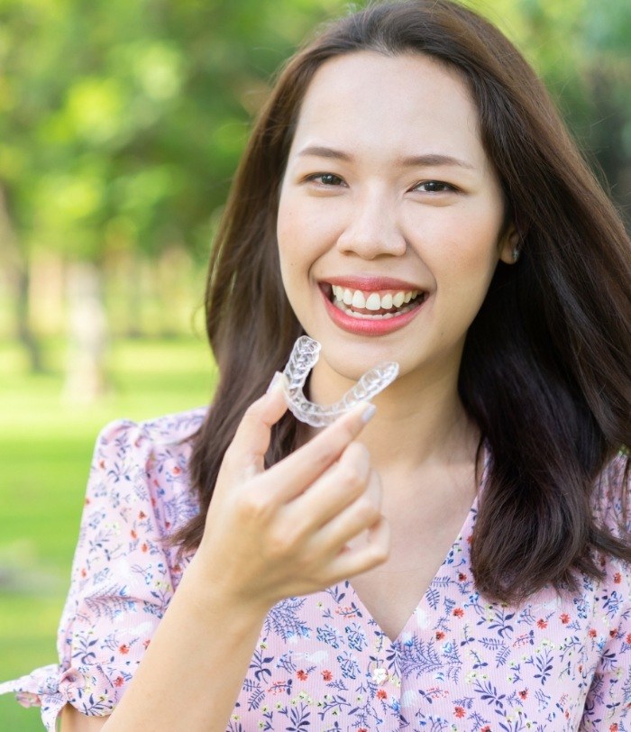 Smiling woman holding Invisalign in Centennial