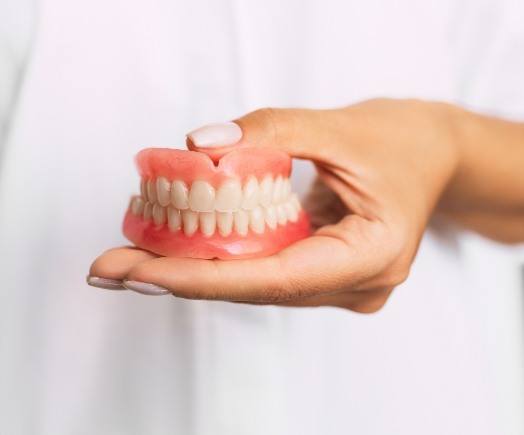 Hand holding a set of full dentures