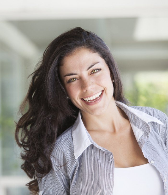 Woman with long dark hair smiling after dental services in Centennial