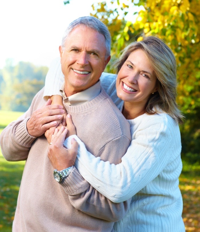 Man and woman hugging outdoors after restorative dentistry in Centennial