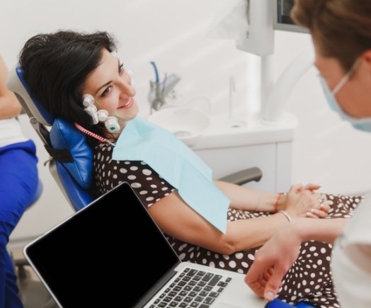 Dentist with laptop talking to a patient in the dental chair