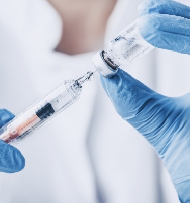 Dentist drawing a syringe with clear liquid