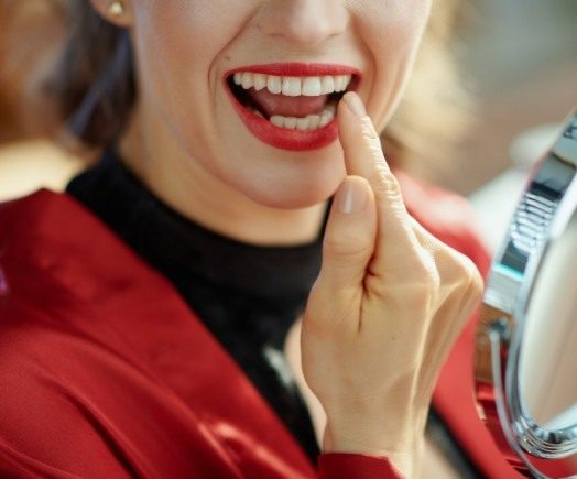 Close up of woman looking at her teeth in a mirror