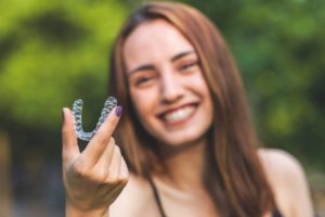 a smiling person holding Invisalign aligners